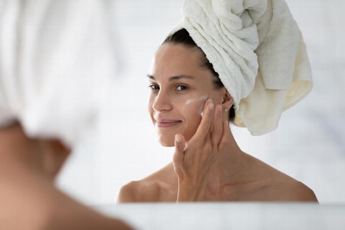 Lady applying face cream after shower